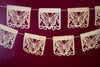 Corn husk papel picado by Ay Mujer. Mariposa design cut into hojas de maiz and strung into banner art.